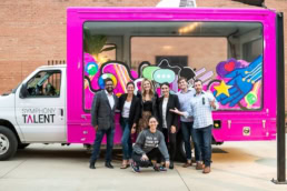 Symphony Talent team posing in front of branded pink truck, event photography Dallas, Texas