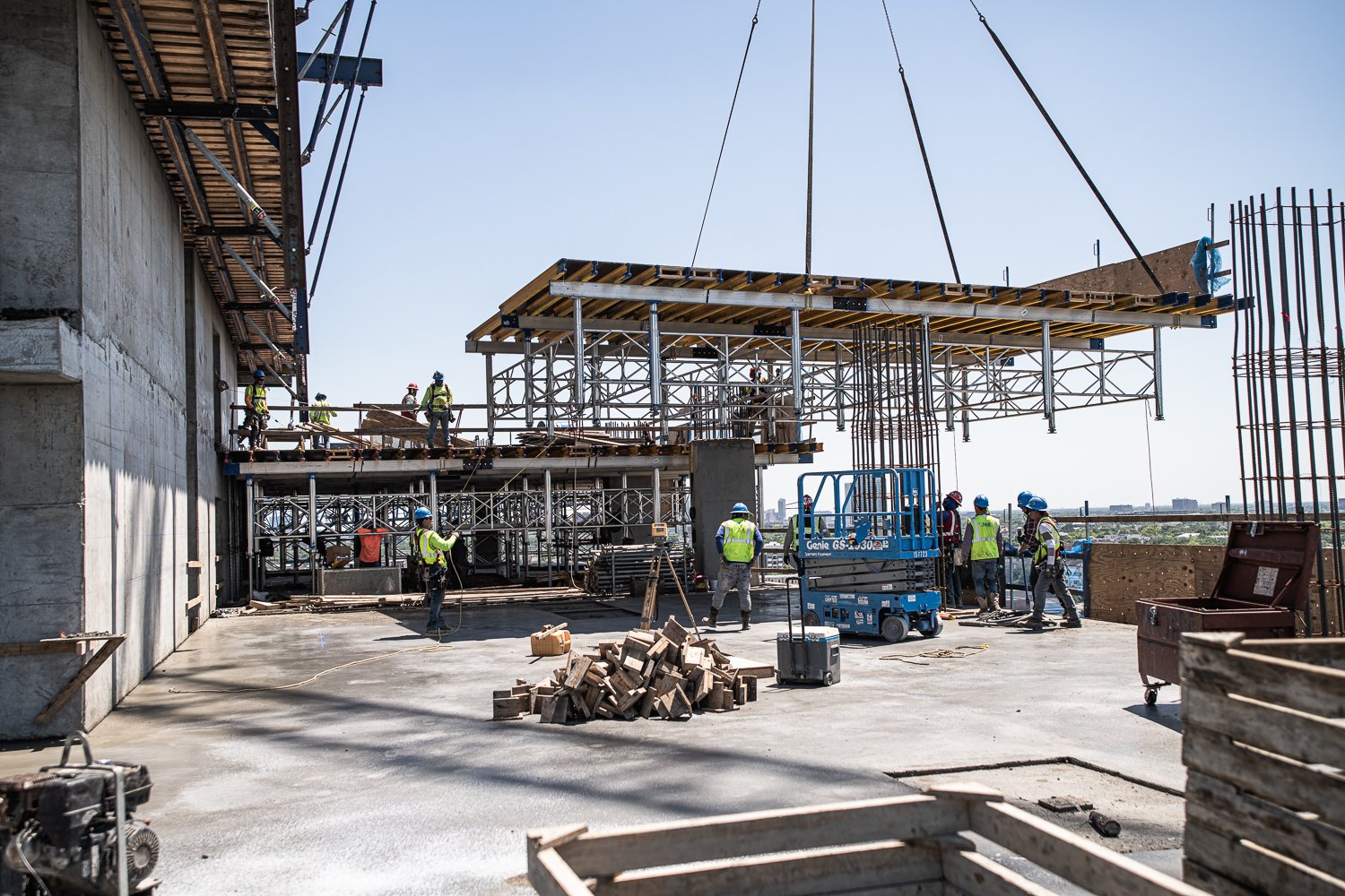 TAS Concrete construction workers guiding crane lift on high-rise job site, industrial photography Houston, Texas