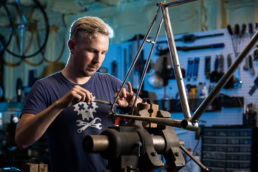 Craftsman building custom bicycle frame in workshop, industrial portrait photography Dallas, Texas