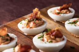 Deviled eggs with bacon and chives on wooden board, food photography Dallas, Texas