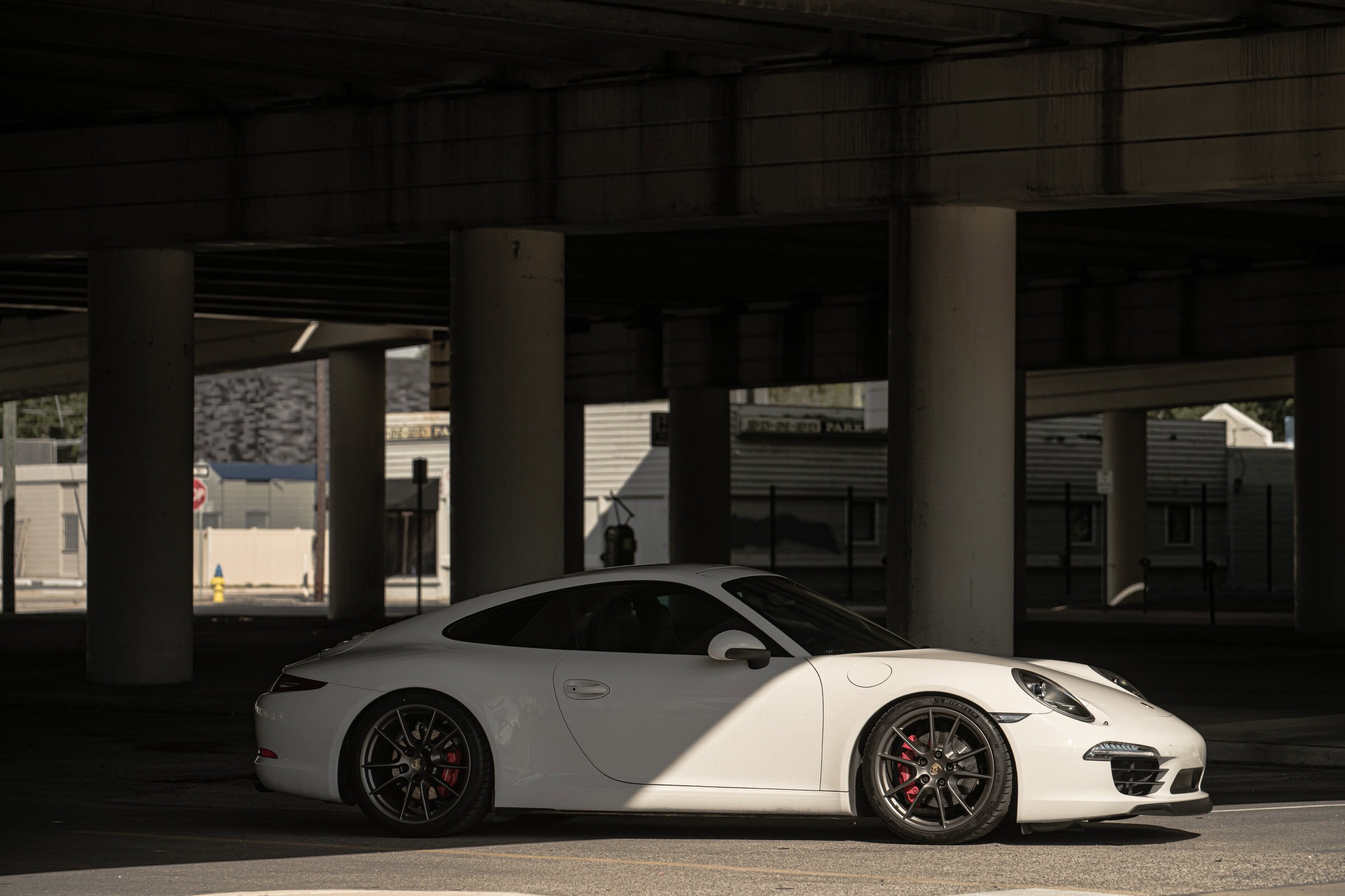 White Porsche 911 Carrera S side profile under overpass, automotive photography Dallas, Texas