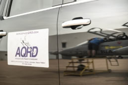 AQRD magnetic sign on vehicle with Air Force jet reflection, aerospace photography Fort Worth, Texas