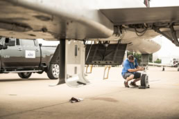 AQRD technician inspecting aircraft landing gear, aerospace photography Fort Worth, Texas