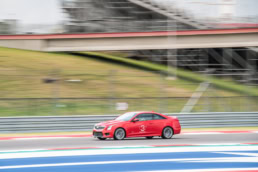 Red Cadillac ATS-V Coupe racing at Circuit of the Americas, automotive photography Austin, Texas