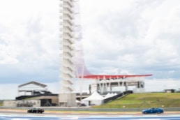 Cadillac sedans racing at Circuit of the Americas with observation tower, automotive photography Austin, Texas