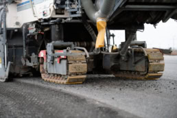 Cold milling machine tracked undercarriage on asphalt, industrial photography Dallas, Texas