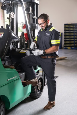 Equipment Depot technician servicing Mitsubishi forklift, industrial photography Dallas, Texas