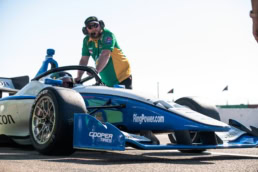Indy Lights race car with RingPower and Cooper Tires livery, crew member on grid, Dallas, Texas