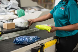 OSM Worldwide worker sorting packages on conveyor belt, commercial photography Dallas, Texas