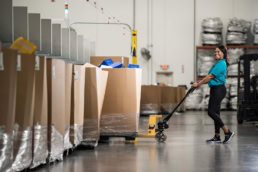 OSM Worldwide warehouse worker pushing CAT pallet jack, industrial photography Dallas, Texas