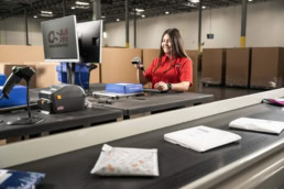 OSM Worldwide warehouse worker scanning packages on conveyor belt, commercial photography Dallas, Texas