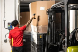 OSM Worldwide warehouse worker scanning pallet with barcode scanner, industrial photography Dallas, Texas