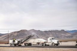 Road milling machine loading asphalt into dump truck, industrial photography Dallas, Texas