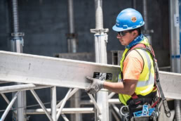 TAS Concrete worker carrying aluminum beam on construction site, industrial photography Houston, Texas