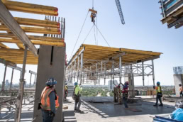 TAS Concrete construction crew guiding crane lift on high-rise jobsite, industrial photography Houston, Texas