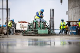 TAS Concrete worker operating ride-on power trowel on fresh slab, industrial photography Houston, Texas
