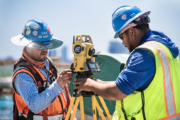 TAS Concrete workers operating Topcon total station on construction site, industrial photography Houston, Texas