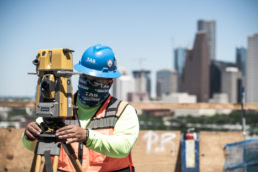 TAS Concrete surveyor using Topcon total station with Houston skyline, industrial photography Houston, Texas