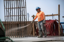 TAS Concrete worker spraying curing compound on fresh concrete, industrial photography Houston, Texas