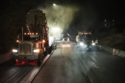 Topcon night paving operation with heavy trucks and steam on highway, industrial photography Fort Worth, Texas