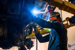 Industrial welder working under a vehicle with sparks flying, commercial photography Dallas, Texas