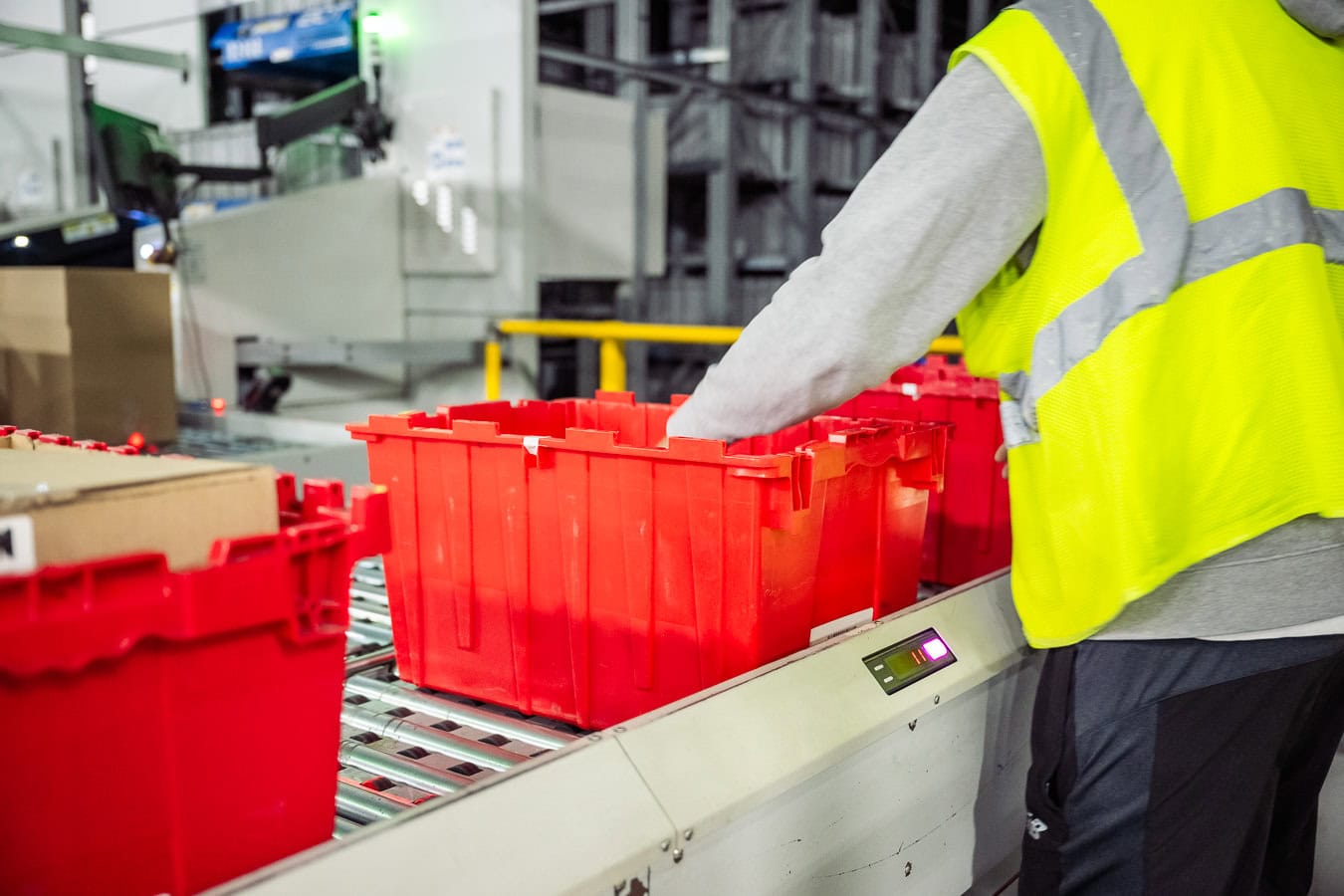 OSM Worldwide warehouse worker sorting red bins on conveyor belt, industrial photography Dallas, Texas