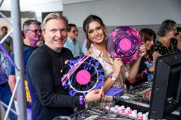 Two guests holding custom painted vinyl records at a Dallas events booth, event photography Dallas, Texas