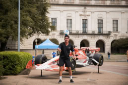 Man juggling soccer ball in front of Formula 1 show car with Hook 'Em Horns livery, event photography Austin, Texas
