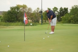 Golfer putting on green with Texas flag pin at Dallas events photography by David Loi Studios