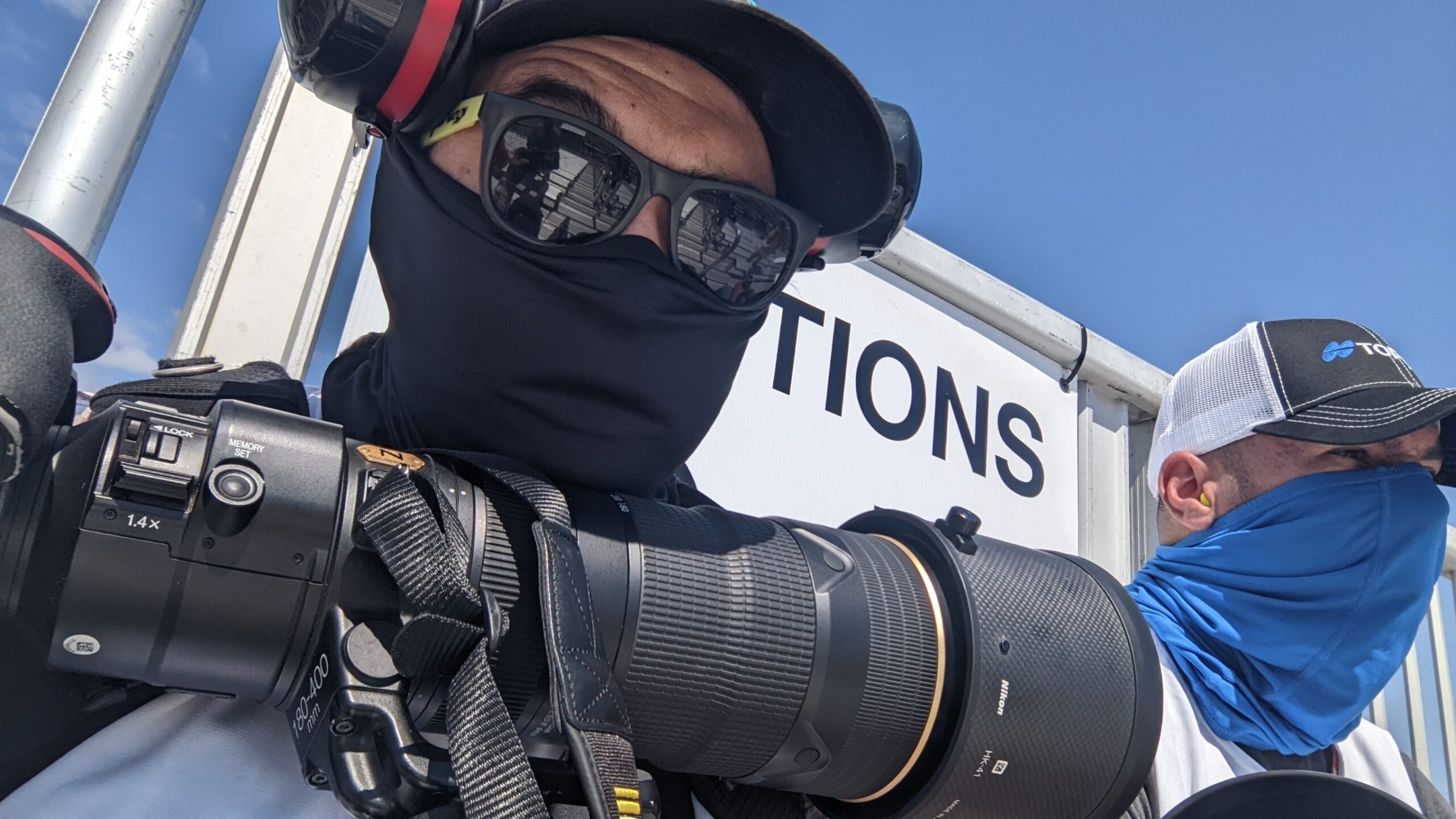 Motorsport photographer with Nikon telephoto lens and 1.4x teleconverter at racing event, Dallas, Texas