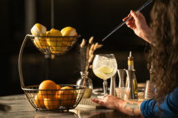 Bartender crafting a gin cocktail with lime at Blackland Distillery, commercial photography Fort Worth, Texas