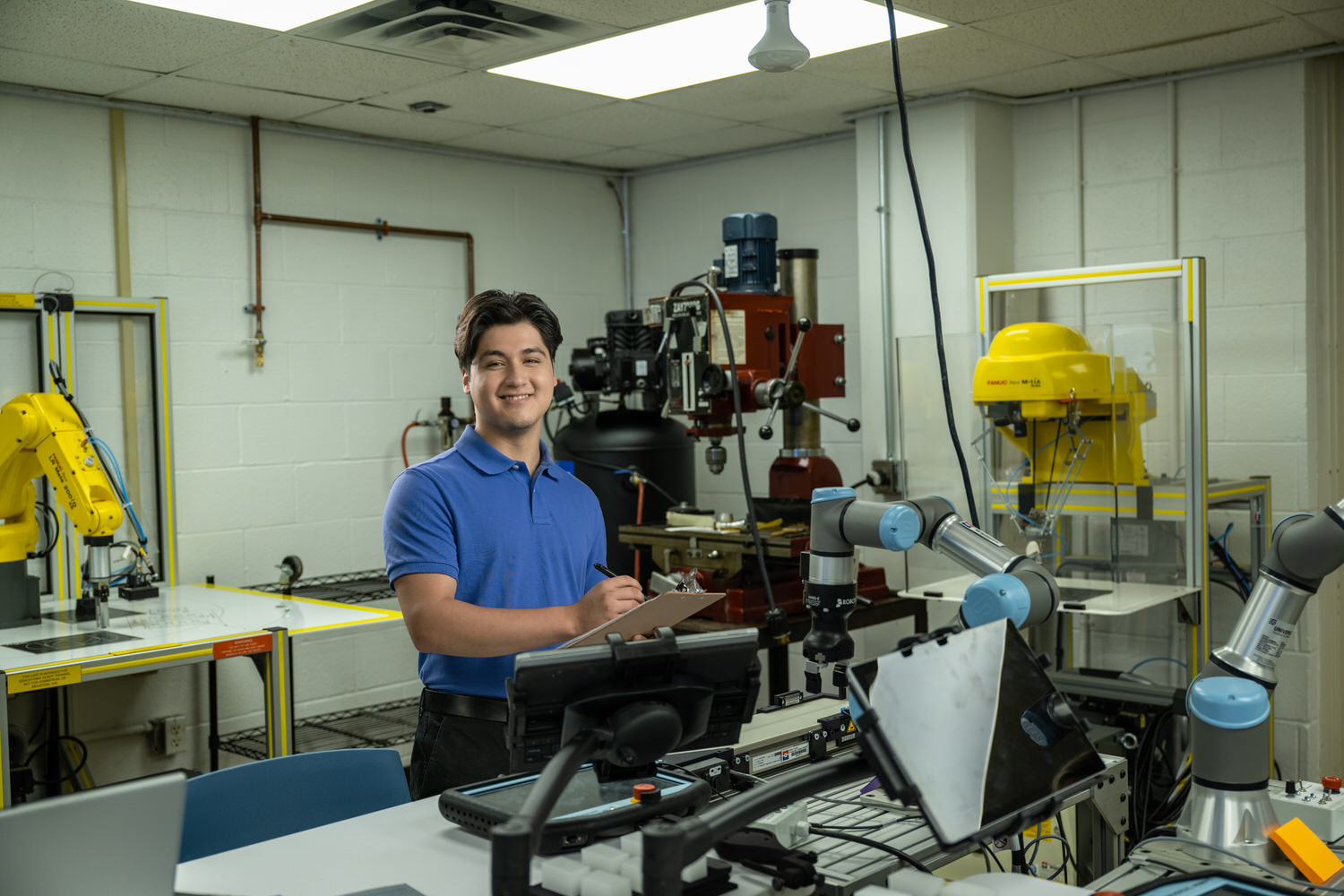 Dallas College robotics student with clipboard in industrial lab, commercial photography Dallas, Texas