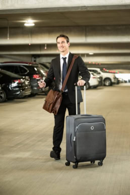 Business traveler with rolling suitcase in DFW Airport parking garage, commercial photography Dallas, Texas