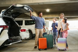 Family loading suitcases into SUV at DFW Airport parking garage, commercial photography Dallas, Texas