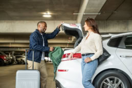 Travelers loading luggage into car at DFW Airport parking garage, commercial photography Dallas, Texas
