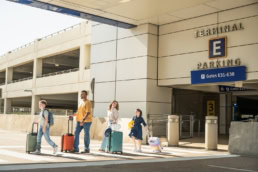 Family with luggage walking at DFW Airport Terminal E, commercial photography Dallas, Texas