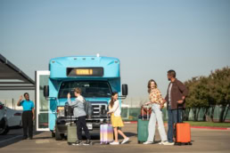 Family with luggage boarding DFW Airport Terminal A shuttle bus, commercial photography Dallas, Texas