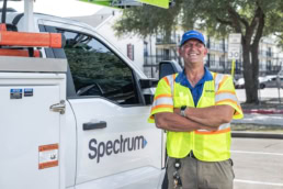 Spectrum technician smiling beside service truck, commercial photography Dallas, Texas