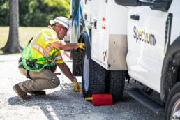 Spectrum technician placing wheel chock on service truck, industrial photography Dallas, Texas