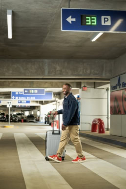 Traveler with rolling luggage in DFW Airport parking garage Level 4, commercial photography Dallas, Texas