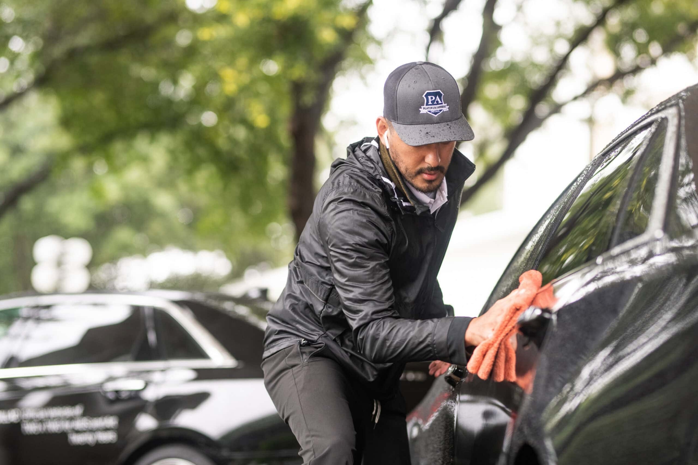 Auto detailer wiping down black car with microfiber cloth, automotive photography Dallas, Texas