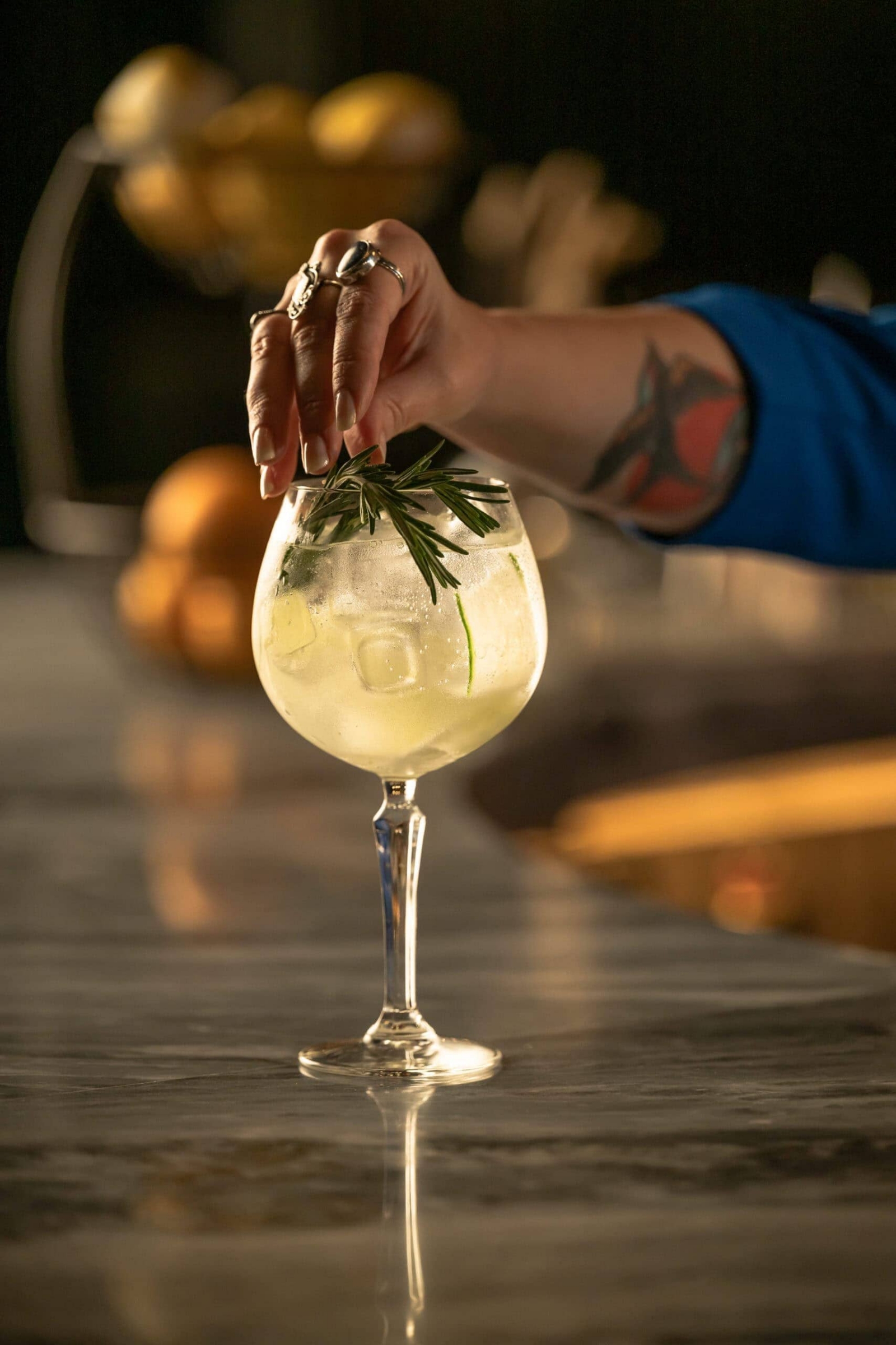 Bartender garnishing a cocktail with fresh rosemary, lifestyle and human interaction photography for hospitality brands in Dallas, Texas by David Loi Studios
