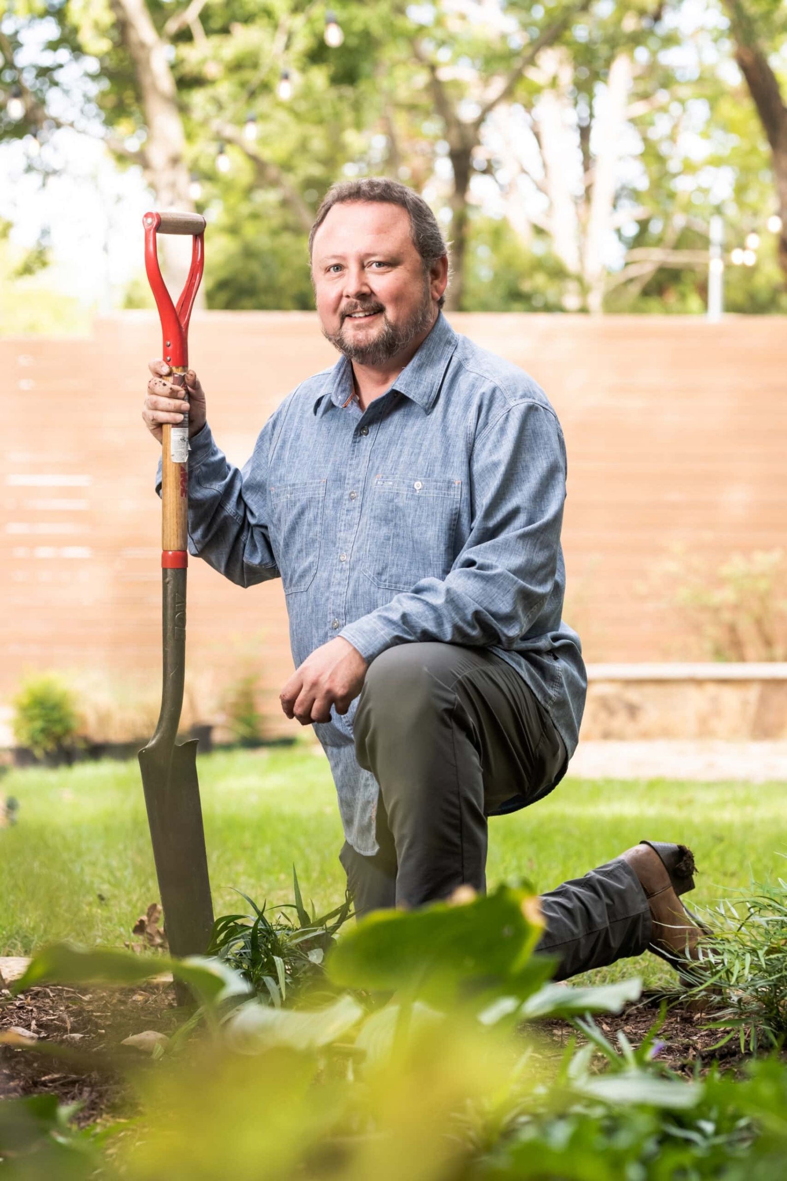 Man kneeling with shovel in garden, portrait photography Dallas, Texas