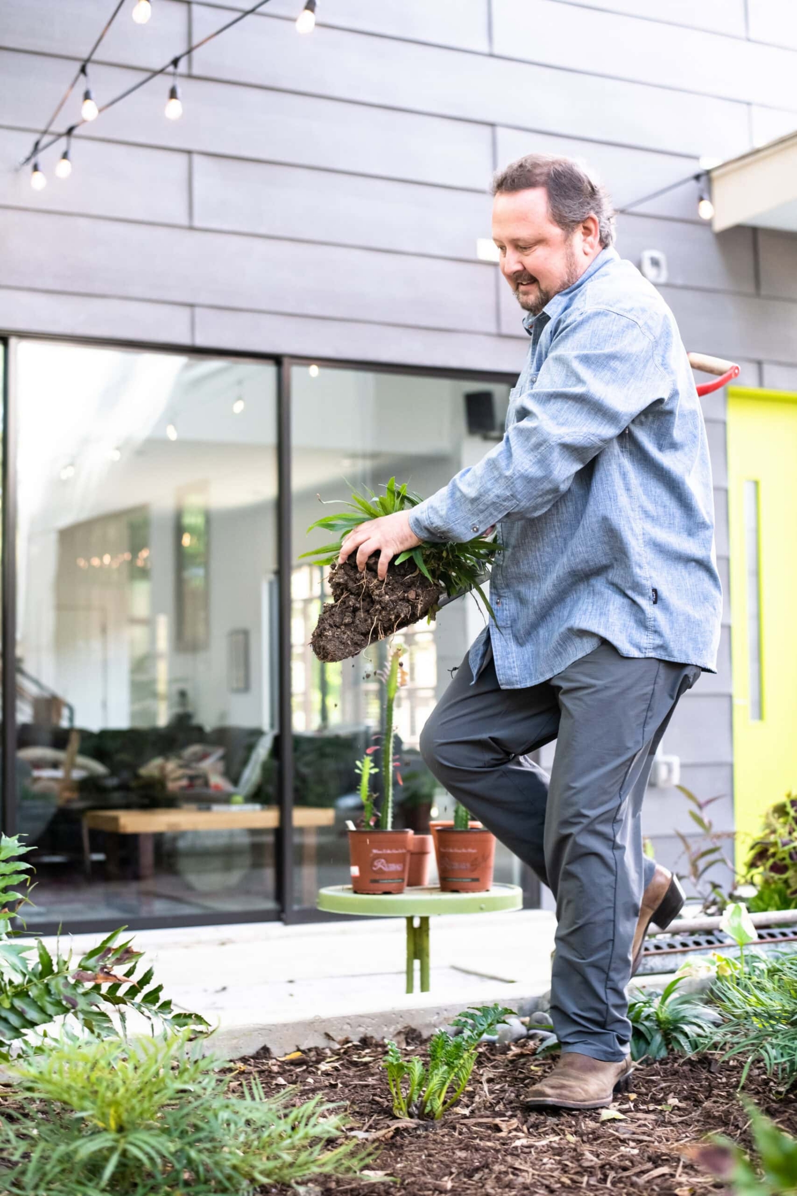 Man planting in a garden bed outside a modern home, lifestyle personal branding photography in Dallas, Texas by David Loi Studios