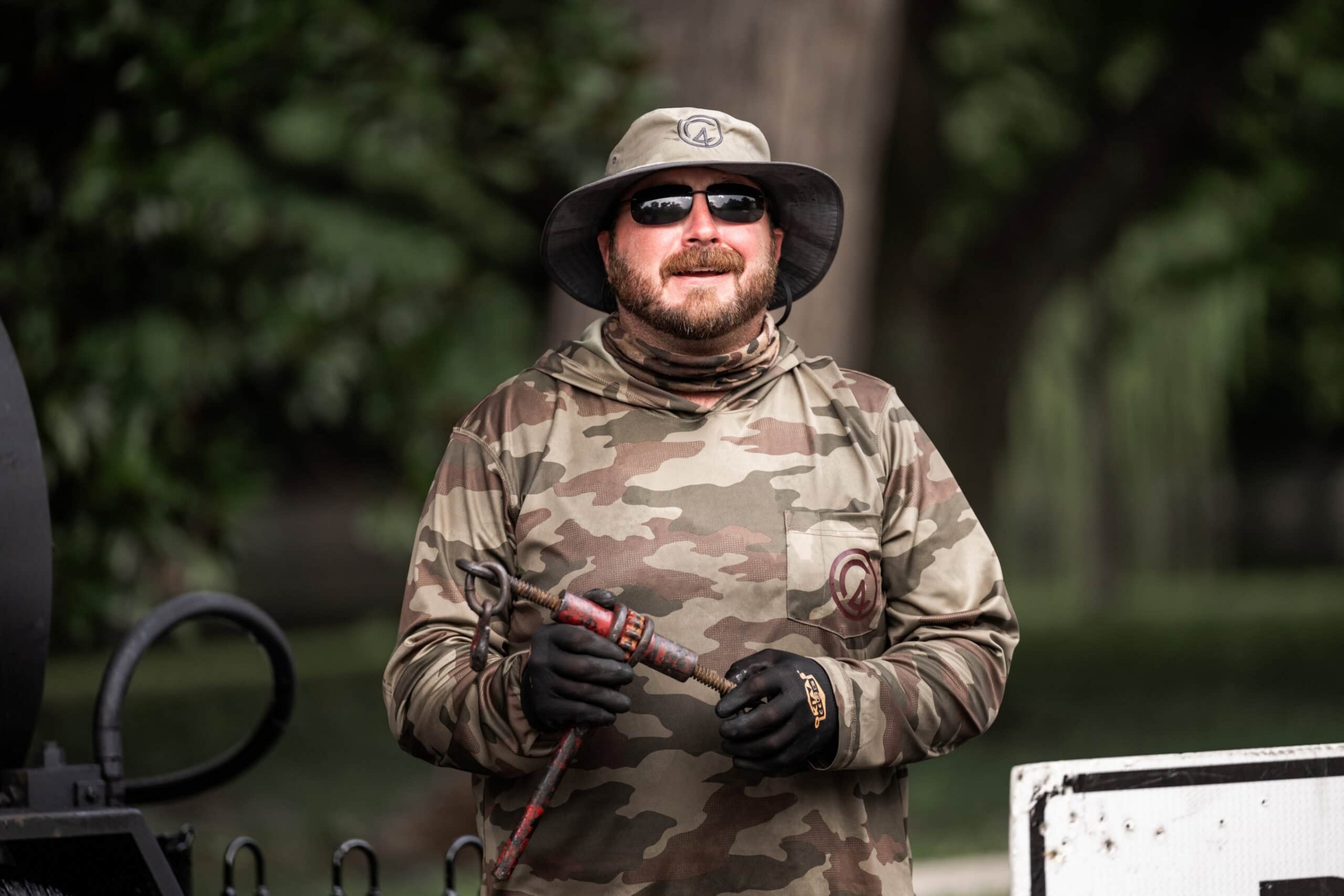 Pitmaster in camo holding smoker tool, commercial portrait photography Dallas, Texas
