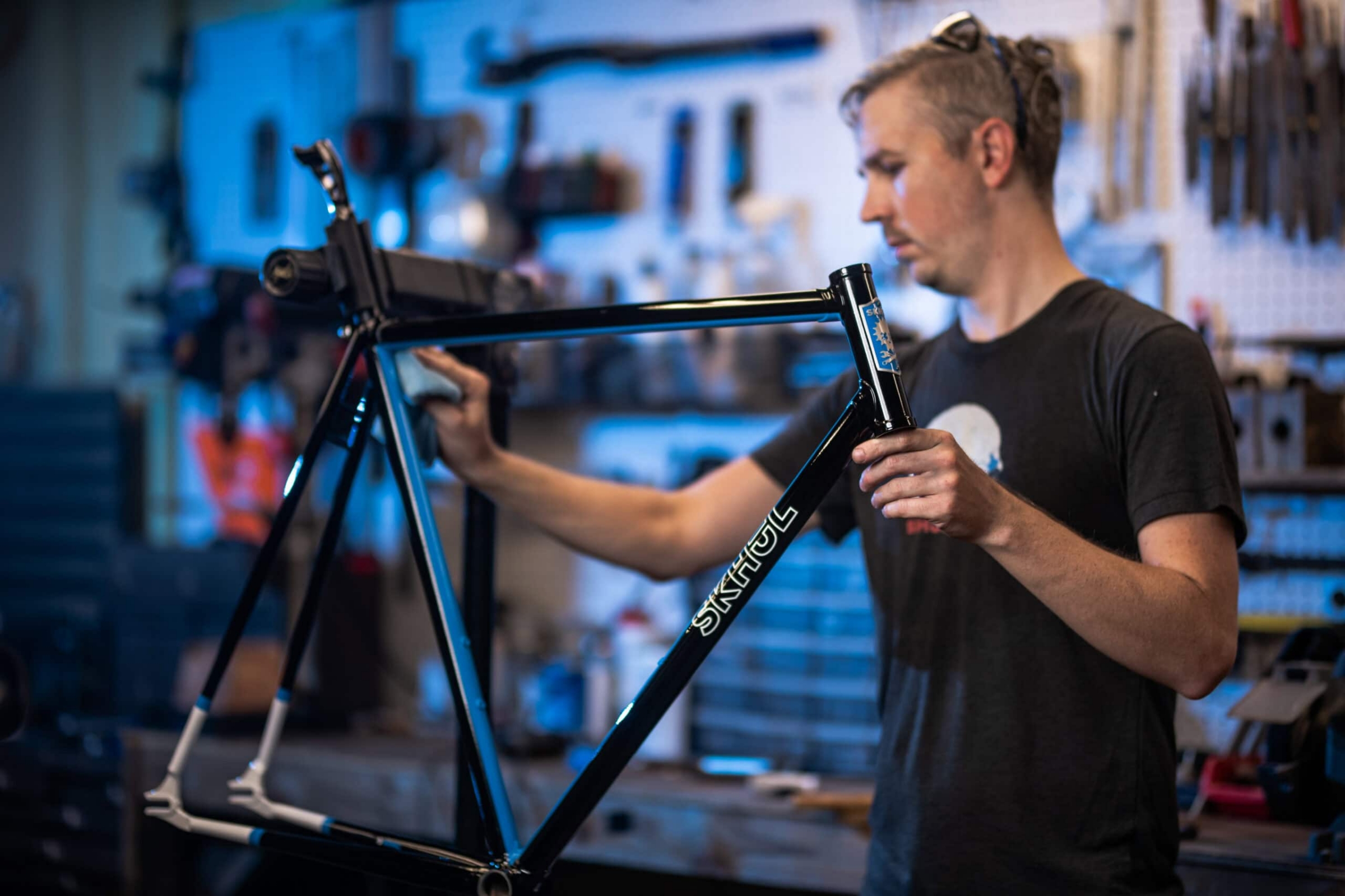 Skhöl bicycle frame builder polishing custom frame in workshop, commercial photography by David Loi Studios