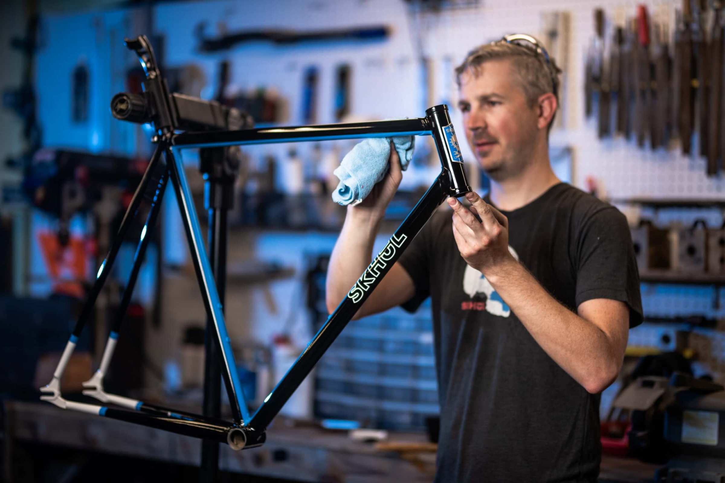 Bike frame builder polishing Skhöl bicycle frame in workshop, commercial photography Dallas, Texas