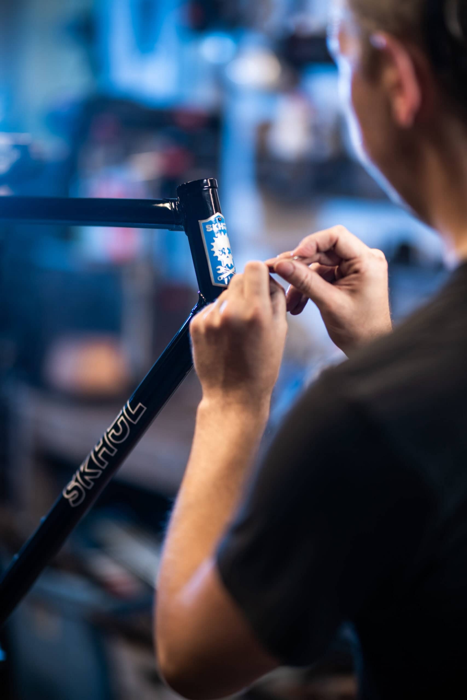 Craftsman applying head badge decal to Skhöl bicycle frame, commercial photography Dallas, Texas