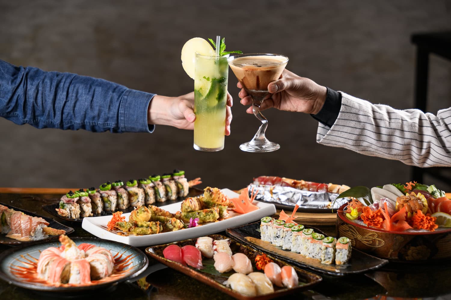 Guests raising cocktails over a sushi spread in a restaurant, hospitality branding photography in Dallas, Texas by David Loi Studios